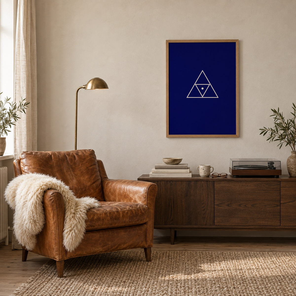 Poster Triad, navy, in an oak frame beside a leather armchair