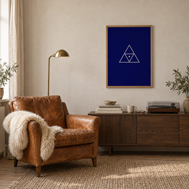 Poster Triad, navy, in an oak frame beside a leather armchair